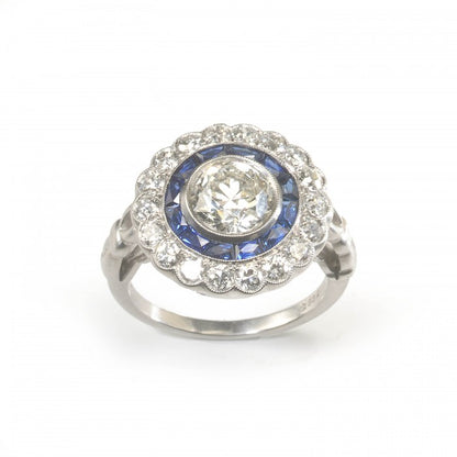 Art Deco Style Diamond and Sapphire Target Cluster Ring; 1.40ct round European old-cut diamond surrounded by twelve French-cut sapphires and an outer border of 0.93cts brilliant-cut diamonds, in platinum