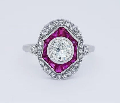 Diamond and Ruby Oval Cluster Dress Ring; 0.89 carat brilliant-cut diamond surrounded by calibre-cut rubies and an outer border of diamonds, 18ct white gold