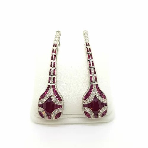 Art Deco Style Ruby, Diamond and Platinum Drop Earrings; featuring oval faceted rubies surrounded by calibre cut rubies and brilliant-cut diamonds set in a geometric design, suspended from an articulated graduated ruby and diamond set drop