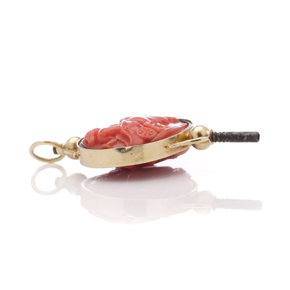 Victorian pocket watch key/pendant in gold and carved coral showing neoclassical scenes.