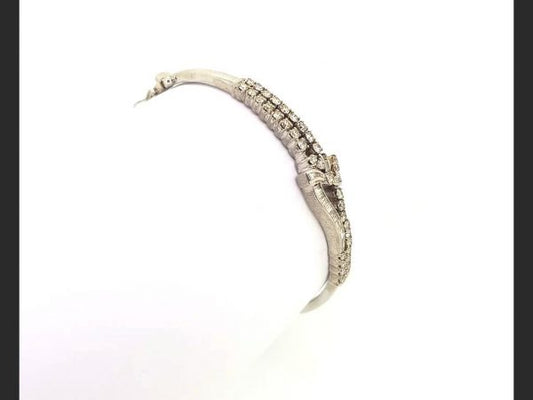 Diamond Bangle; Double row of round cut diamonds and baguette cut diamonds culminating in a delicate bow design, set in 18ct white gold