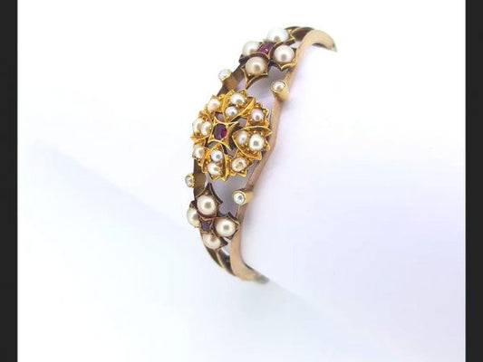 An Antique Edwardian Split Pearl and Ruby Bangle with central floral design and flanked by similar design, on detailed 15ct gold bangle
